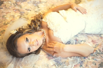 Красивый свадебный макияж для серых глаз и модная свадебная прическа с локонами на бок, цветами и фатой для русых волос
